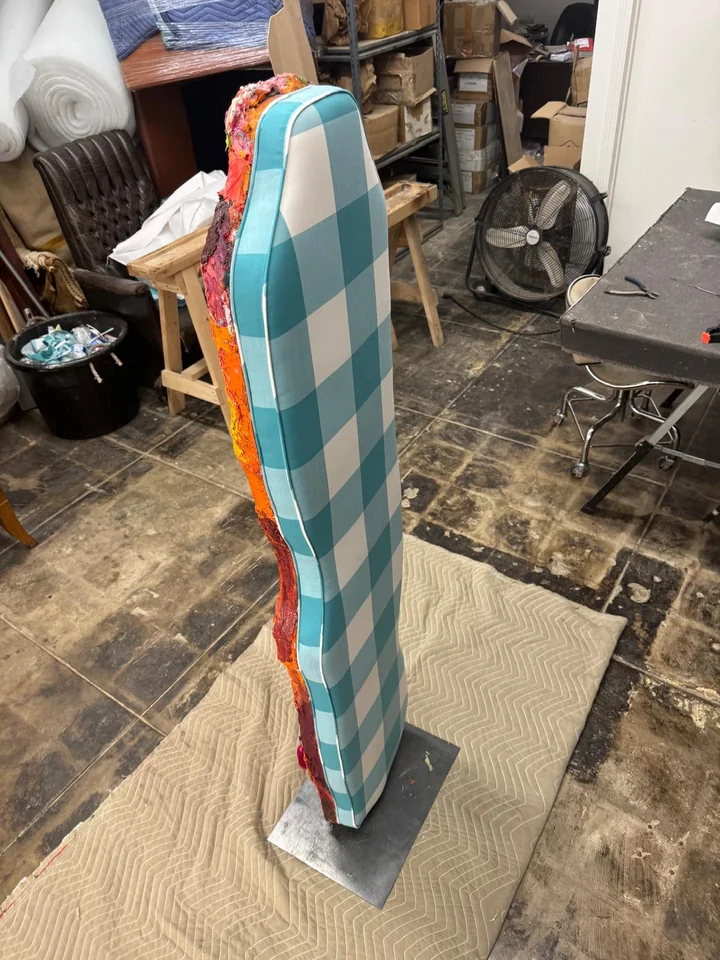 Side view of a tall upholstered panel with turquoise and white checks and a colorful edge
