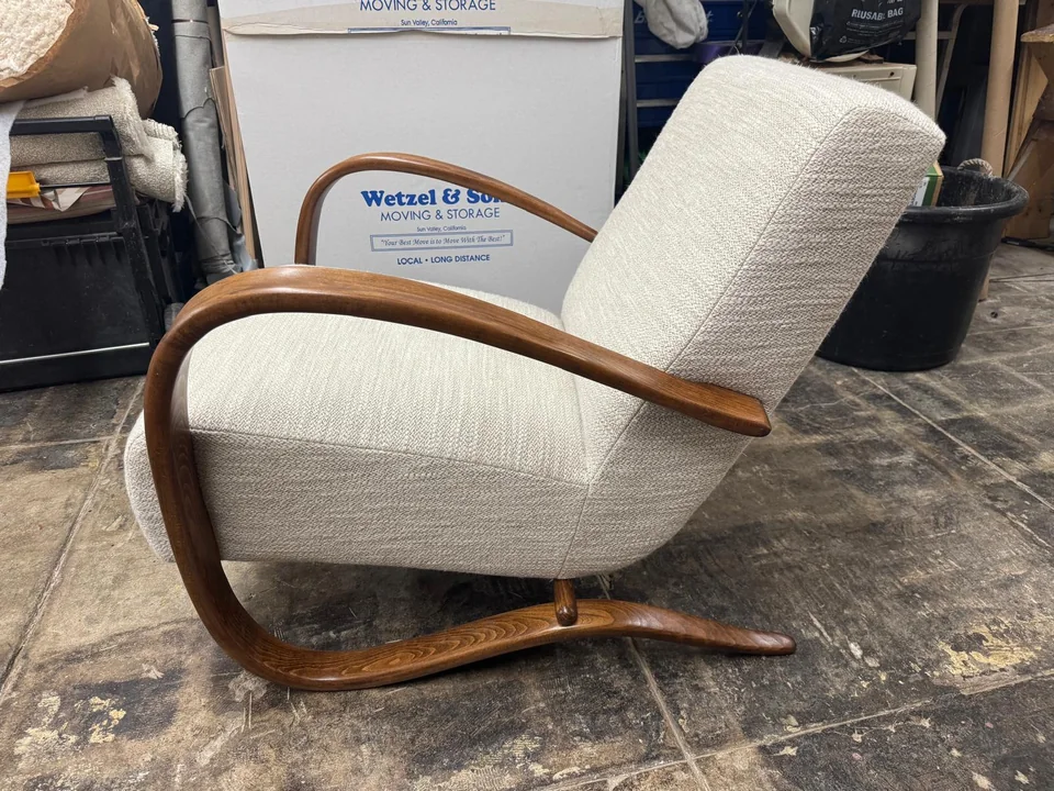 Side view of the cream lounge chair showing its curved wooden frame