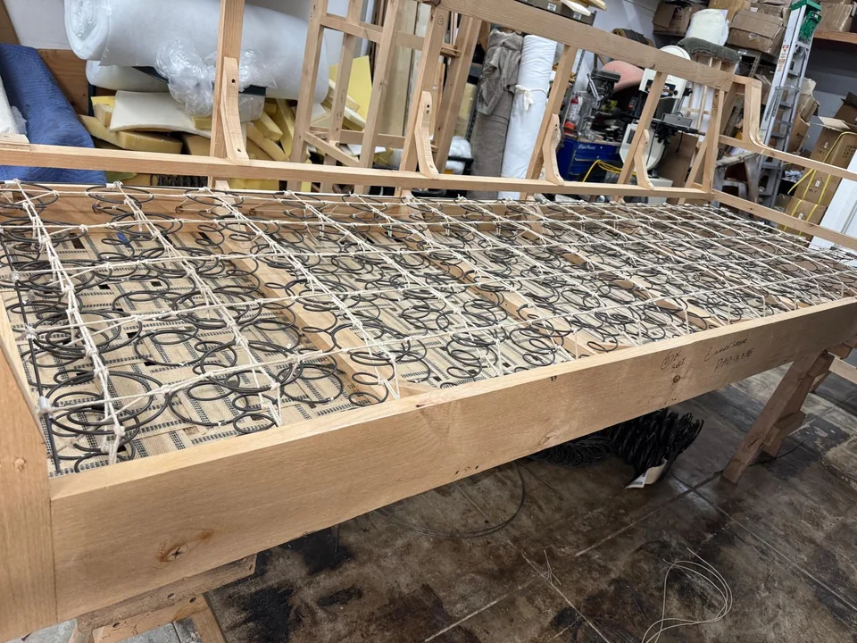 Wooden furniture frame with an exposed grid of tied coil springs