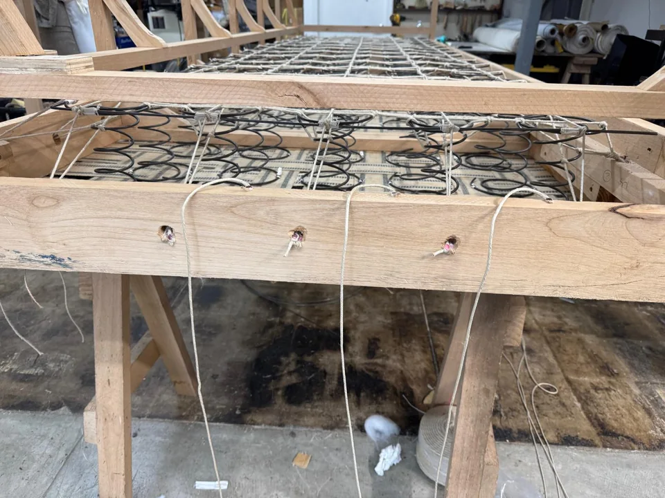 Close view of tied coil springs and twine inside a wooden furniture frame