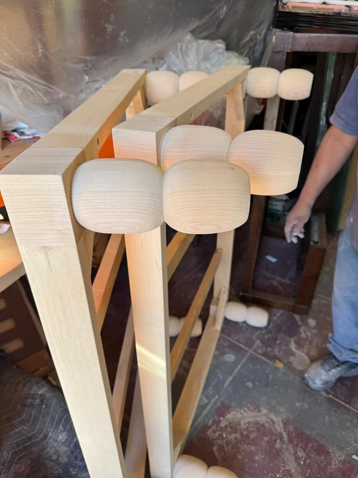 Pale wooden frame components with rounded ends arranged in the workshop