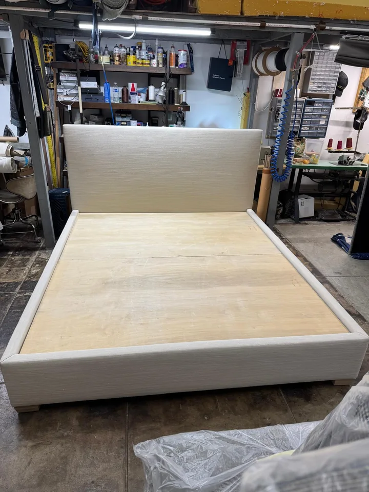 Neutral upholstered bed frame and headboard with an exposed wooden platform