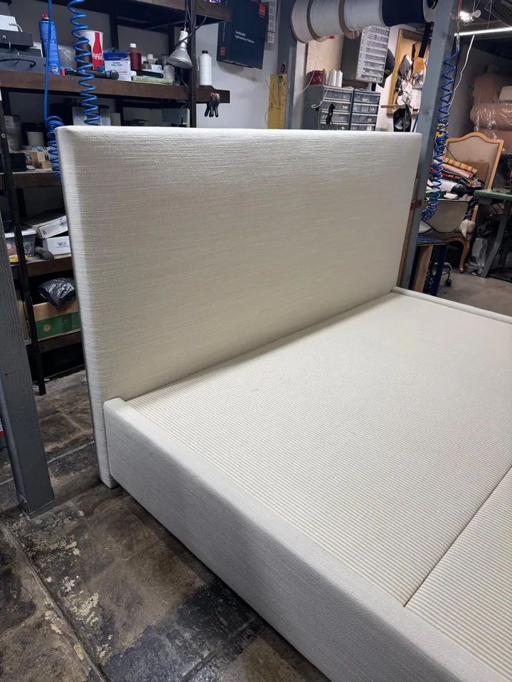 Close view of a neutral upholstered headboard and matching bed surround