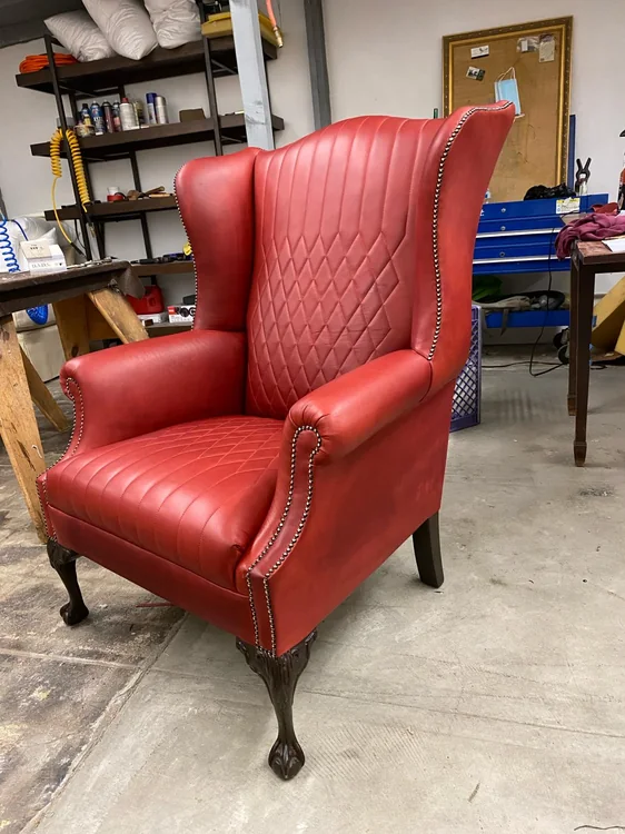Red upholstered wingback chair with diamond stitching and nailhead trim